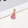 Macro detail of a gold guitar pendant with micro-set pink zircons for DIY jewelry - Rose Red Guitar Style