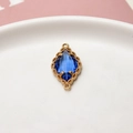 Detalle macro del colgante de cristal azul marquesa con marco floral de oro fino - Azul Claro