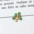 Macro detail of a gold tree-shaped pendant charm set with vibrant green cubic zirconia - Green Christmas Tree
