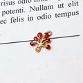 Detailed view of a gold tree pendant with red cubic zirconia on a minimalist paper background - Red Christmas Tree