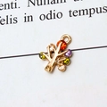 Macro shot of a golden tree-shaped jewelry pendant with multi-colored zircons on book pages - Tree Multicolor