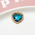 Macro-detail van een hartvormige blauwgroene kristallen hanger met gouden kanten zetting - Pauwblauw
