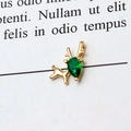 Macro shot of gold deer pendant with a green teardrop-shaped gemstone on white paper - Green Reindeer