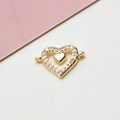Dettaglio macro di un connettore a cuore dorato con zirconi scintillanti per gioielli fai-da-te - Bianco