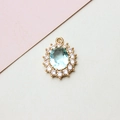 Detail of oval light blue gemstone pendant with white zircon halo and gold setting - 14*19mm / Light Blue