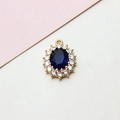 Close-up of oval gold pendant with blue gemstone and sparkling white zircon halo - 14*19mm / Dark Blue