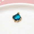 Macro view of teardrop blue faceted gemstone pendant with gold-plated hexagonal claw setting - Peacock Blue