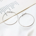 Macro detail of large polished silver-tone circular hoop earrings on white fabric - 50mm / White Gold
