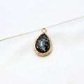 Macro detail of gold-plated teardrop pendant with iridescent resin and ripple edge frame - Black Shell Style