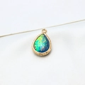 Macro shot of gold-plated teardrop opal pendant with detailed woven texture on silk - AB Aurora Blue