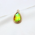 Macro shot of gold-plated teardrop resin opal pendant with intricate woven texture - AB Aurora Red