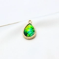 Detailed close-up of a gold-plated teardrop resin opal pendant with engraved edges - AB Aurora Black