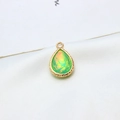 Detail of a gold-plated teardrop pendant with green resin opal inlay on white silk fabric - AB Aurora Pale Green