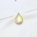 Macro shot of gold plated teardrop resin opal pendant with textured metallic borders - AB Aurora White
