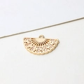 Macro detail of a gold fan-shaped jewelry pendant with hollow design and inlaid rhinestones - Fan