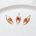 Macro view of gold-rimmed resin leaf pendants with dried flowers and gold foil details - Marquise / Pink