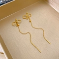 Dettaglio di orecchini a fiocco dorati con nappe su una scatola di gioielli raffinata - Pendaglio a Fiocco / Oro