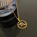 Gold Scorpio zodiac necklace with sparkling crystal pendant on a black reflective surface - Scorpio / Gold
