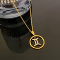 Gold-plated Gemini zodiac pendant necklace with white crystals on a black reflective surface - Gemini / Gold