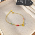 Detail view of a gold titanium bracelet featuring colorful beads and a shell charm - Scallop Tricolor Bead Style (X2017)