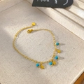Detail of gold chain bracelet with star charms and turquoise beads on fabric display - Star Turquoise Bead Style (X2008)