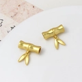 Macro detail of matte gold bamboo pendants on white ceramic plate with calligraphy background - Long Bamboo Section Leaf (06#7*18mm)