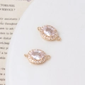 Nahaufnahme von ovalen Anhängern mit rosa Zirkonia in goldener Mikropavé-Fassung - Weiß