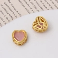 Macro view of gold heart beads with pink cat eye stone and hollow floral details - Heart Shape / Antique Gold - Pink