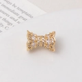 Macro shot of gold-plated bow-shaped jewelry clasp with sparkling zircon inlay - White