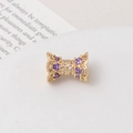 Macro shot of gold-plated hourglass bead with purple zircon and wavy pattern detail - Purple