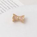 Macro view of a luxury gold bow charm with sparkling pink and white pavé zircon stones - Pink