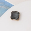 Macro detail of dark grey faceted square stone pendant with gold four-prong setting - Gray