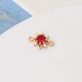 Macro view of gold sun pendant with red zircon center and small white crystals - Red