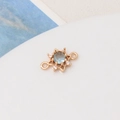 Macro shot of gold-plated sun pendant with light blue zircon and symmetrical double loops - Light Blue