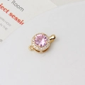 Detailed macro view of a gold-plated circular clasp with a faceted pink zircon stone - Pink Round (10x15mm)