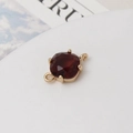 Vue macro d'un connecteur en pierre rouge foncé avec anneaux dorés pour bijoux DIY - Rose Lotus
