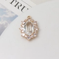 Macro shot of oval crystal pendant with gold setting and small surrounding rhinestones - White