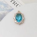 Detail of 10x14mm oval blue crystal pendant with gold-plated setting and zircon halo - Lake Blue