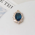Detailansicht ovaler blauer Kristallanhänger mit Goldbeschichtung und Zirkonia-Rand - Pfauenblau