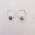 Dettaglio di orecchini a cerchio in argento con sfere di cristalli viola pavé su tessuto - Orecchini / Viola Chiaro