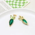 Macro view of carrot-shaped gold pendants with green gemstones and side engraving - Carrot Style / Green