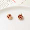 Macro view of gold hollowed spherical charm with vintage pattern and red crystal bead - 9*13mm / Red