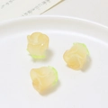 Macro view of cream resin rose petal charms with green base for DIY jewelry crafting - Yellow