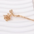 Detailed macro view of a golden rose flower hair pin with realistic metal petals and leaves - Camellia Style