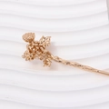 Close-up of golden vintage flower hair stick with detailed petals on wavy white background - Daisy Style