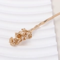 Close-up of golden bronze flower hair pin with intricate petals and textured wavy stick - Pomegranate Flower Style