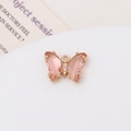 Macro detail of a small pink butterfly pendant with gold plating and zircon inlay for DIY jewelry - Champagne