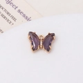 Détail d'un pendentif papillon en zircon violet doré sur une plaque en céramique blanche - Violet Foncé