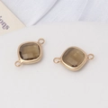 Vue macro de breloques en cristal brun fumé avec monture dorée et doubles anneaux de fixage - Vert olive
