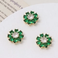 Macro detail of three gold-plated daisy charms with green crystal petals and zircon centers - Green